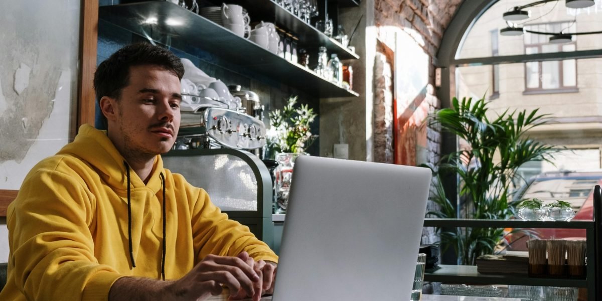 A person happily engaged with their phone in a coffee shop, benefiting from a strong, reliable WiFi connection.