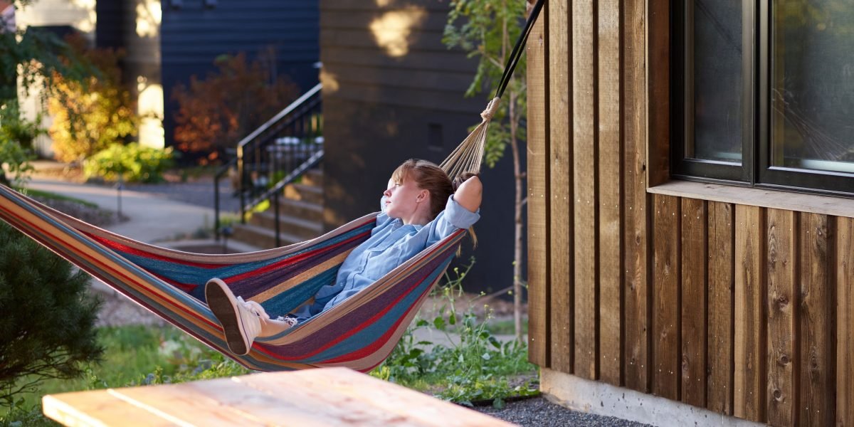 A person enjoys streaming content while relaxing comfortably in a backyard hammock, thanks to extended WiFi coverage.